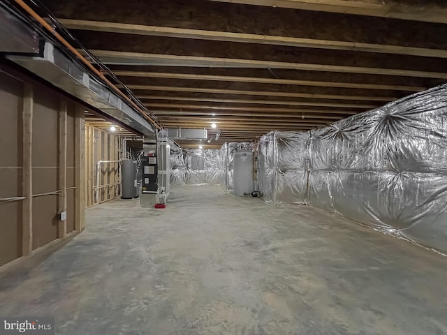 basement with heating unit, gas water heater, and electric water heater