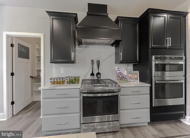 kitchen featuring premium range hood, appliances with stainless steel finishes, and light wood-type flooring