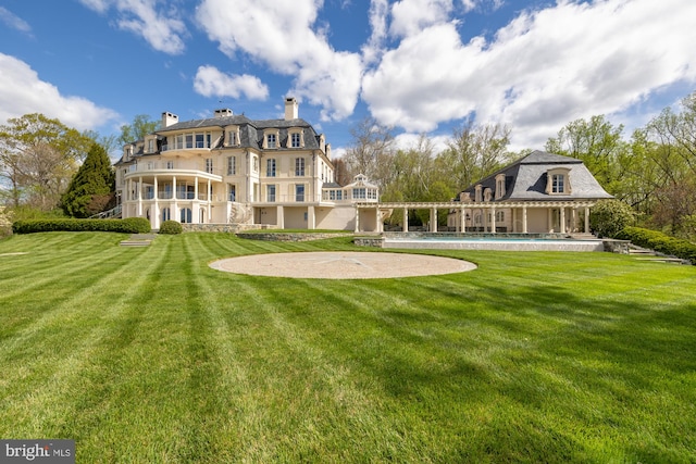 rear view of property featuring a swimming pool and a yard