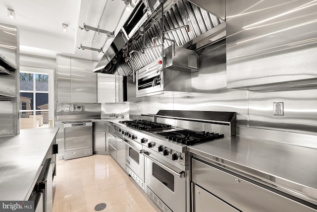 kitchen with light tile patterned floors, backsplash, stainless steel counters, and range with two ovens