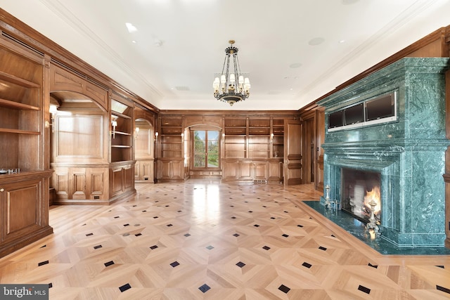 unfurnished living room featuring ornamental molding, a high end fireplace, and a notable chandelier