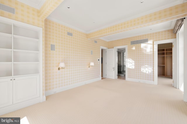 unfurnished bedroom with ornamental molding, a walk in closet, light colored carpet, and a closet