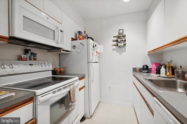 kitchen featuring white appliances, light tile flooring, white cabinetry, and sink