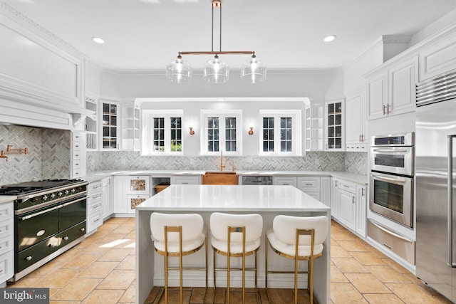 kitchen featuring a center island, tasteful backsplash, white cabinets, and premium appliances