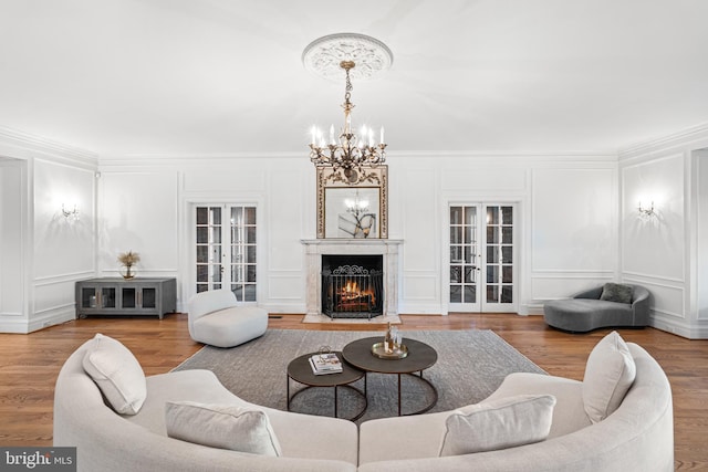 living room with a premium fireplace, french doors, crown molding, and wood-type flooring