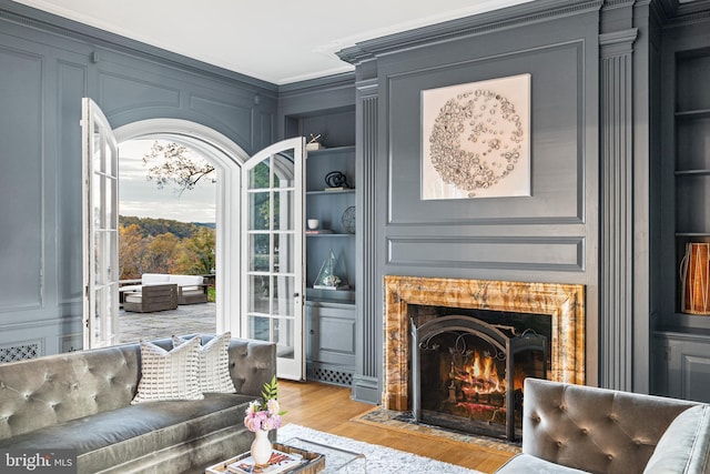 living area with ornamental molding, built in features, and light wood-type flooring