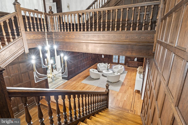 stairway featuring wood-type flooring and an inviting chandelier