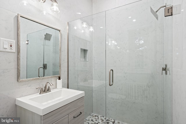 bathroom featuring a shower with door and vanity