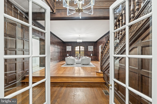 interior space with crown molding, dark wood-type flooring, a chandelier, and wood walls