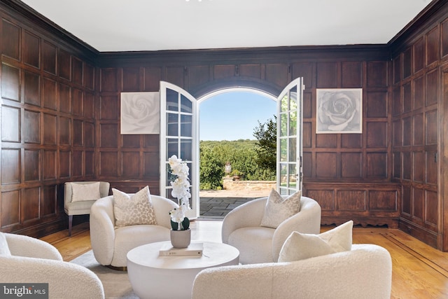 living area with ornamental molding, light hardwood / wood-style flooring, and wood walls