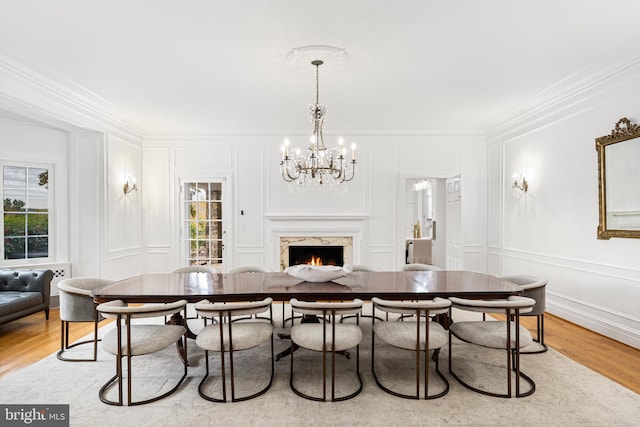 dining area featuring ornamental molding, a chandelier, light hardwood / wood-style flooring, and a fireplace