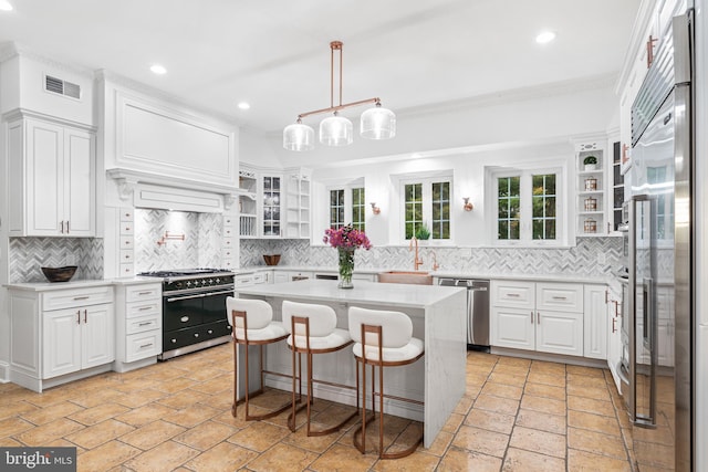 kitchen with high quality appliances, a kitchen breakfast bar, a center island, white cabinets, and tasteful backsplash