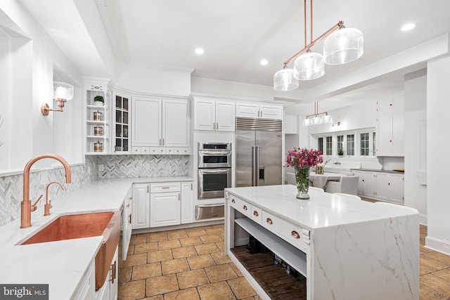 kitchen with a kitchen island, decorative backsplash, white cabinetry, appliances with stainless steel finishes, and light stone counters