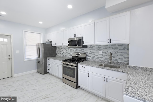 kitchen featuring sink, stainless steel appliances, white cabinetry, and light tile floors