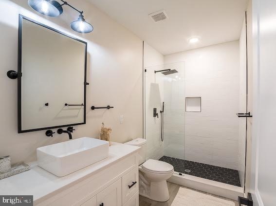 bathroom featuring a shower with shower door, toilet, and oversized vanity