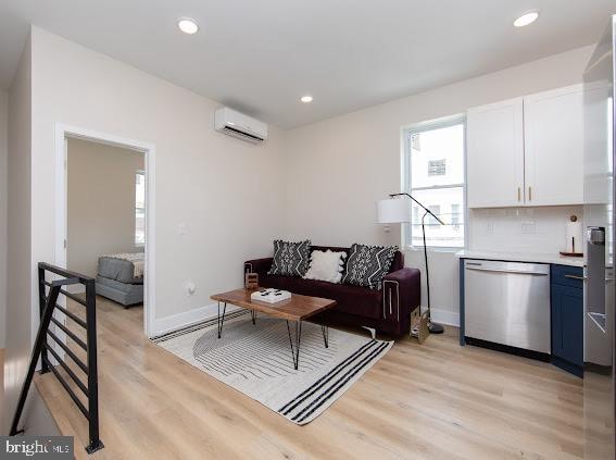 living room featuring a wall unit AC and light hardwood / wood-style floors