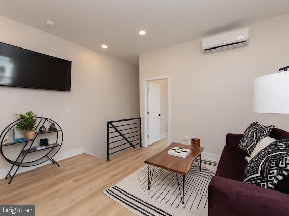 living room featuring a wall mounted air conditioner and light wood-type flooring