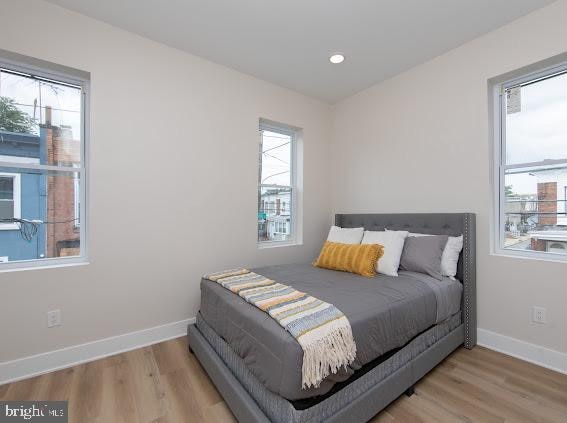 bedroom with light hardwood / wood-style floors and multiple windows