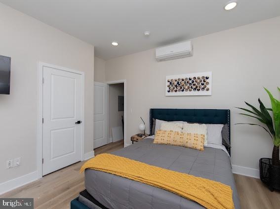 bedroom with an AC wall unit and light hardwood / wood-style flooring