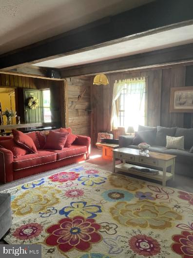 living room with beamed ceiling and wood walls