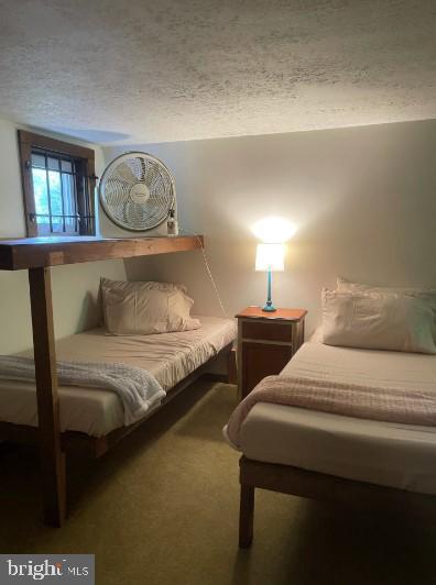 bedroom featuring a textured ceiling and dark colored carpet