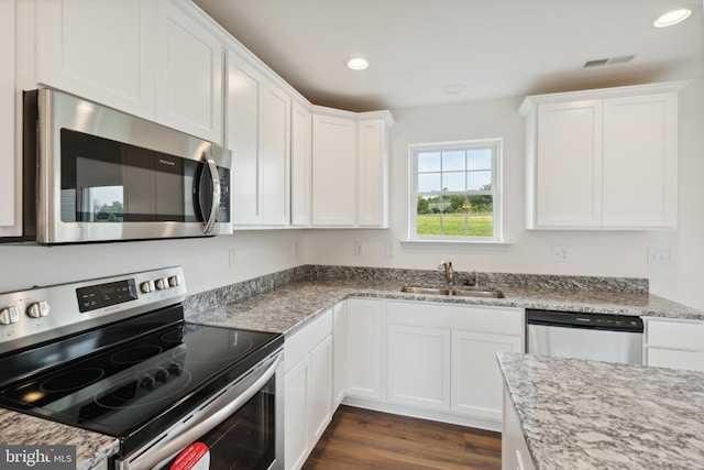 kitchen with light stone counters, stainless steel appliances, sink, and white cabinets