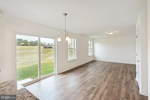 unfurnished dining area with a notable chandelier and dark wood-type flooring