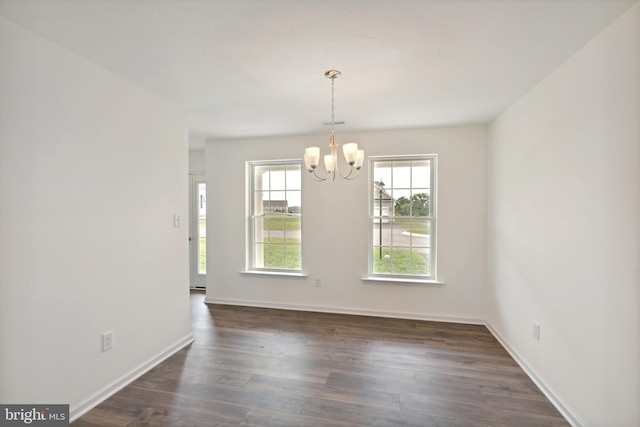 unfurnished dining area featuring an inviting chandelier and dark wood-type flooring