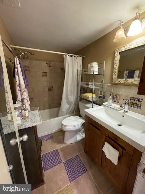 full bathroom featuring vanity, tile patterned flooring, decorative backsplash, toilet, and shower / bathtub combination with curtain