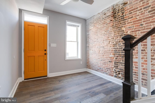 entryway featuring ceiling fan, brick wall, dark wood-type flooring, and a wealth of natural light