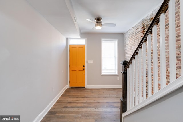 entryway with brick wall, dark hardwood / wood-style floors, and ceiling fan