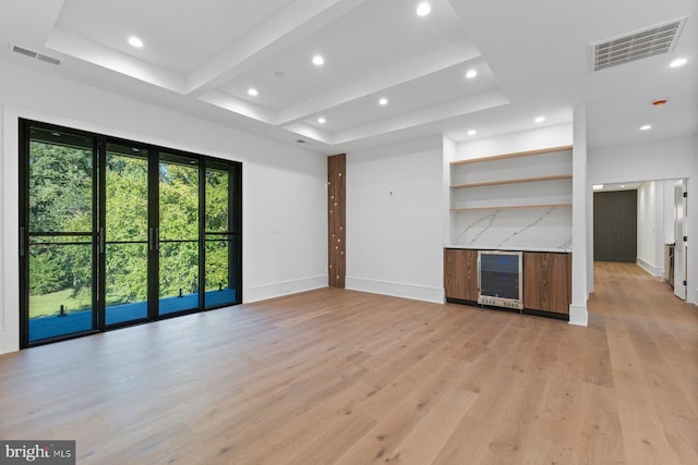 unfurnished living room with bar area, light hardwood / wood-style flooring, and beverage cooler