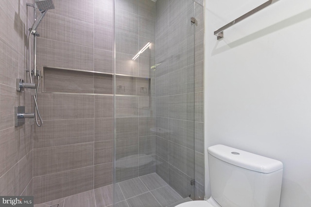 bathroom featuring toilet and a shower with shower door