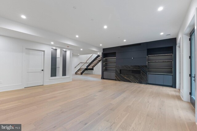 living room with a raised ceiling and light wood-type flooring