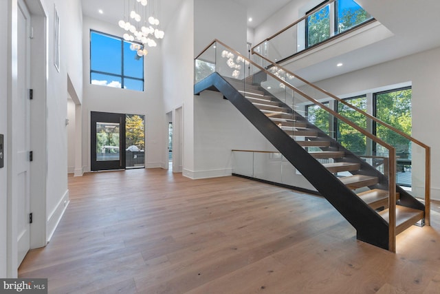 foyer entrance with hardwood / wood-style floors, a notable chandelier, a high ceiling, and a wealth of natural light