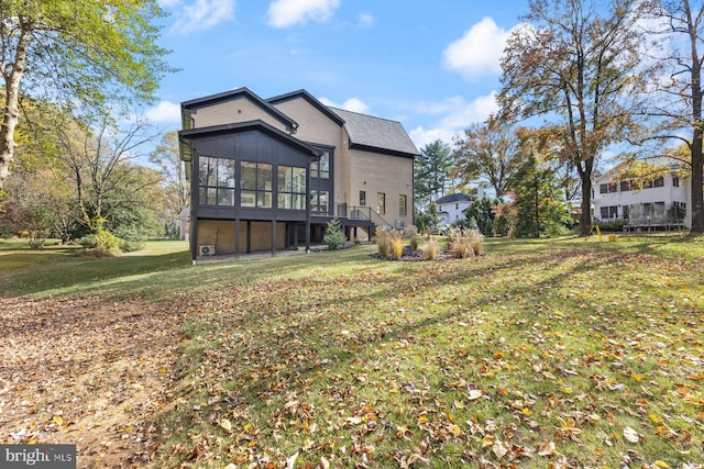 back of house featuring a sunroom and a lawn