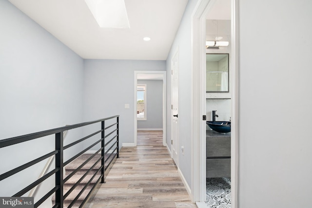 hall featuring light hardwood / wood-style flooring, sink, and a skylight