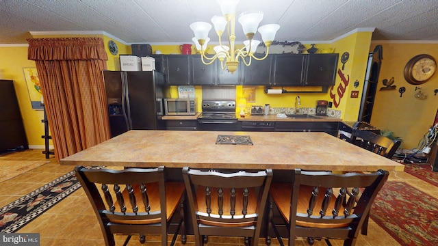 kitchen featuring a notable chandelier, light tile flooring, a breakfast bar, ornamental molding, and black appliances