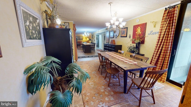 tiled dining area with an inviting chandelier, a textured ceiling, and ornamental molding