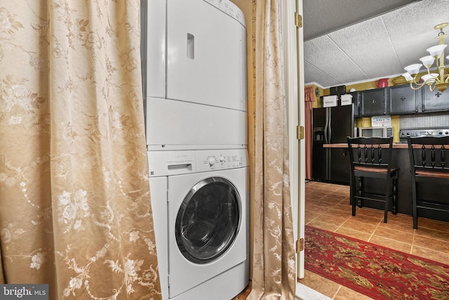 clothes washing area featuring stacked washer and clothes dryer and tile flooring