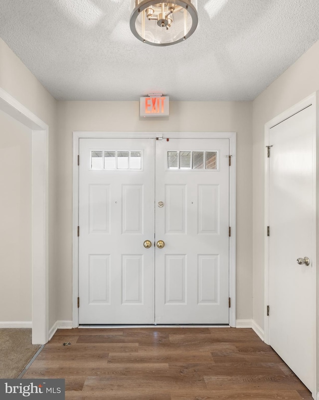 carpeted entrance foyer featuring an inviting chandelier and a textured ceiling