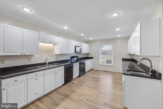 kitchen with black appliances, sink, and light hardwood / wood-style flooring