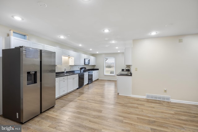 kitchen with sink, light wood-type flooring, white cabinets, and black appliances