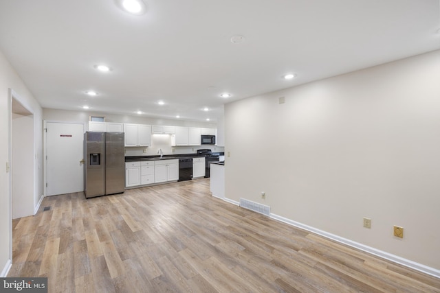 kitchen with white cabinets, light hardwood / wood-style flooring, black appliances, and sink