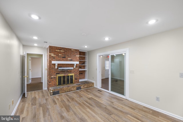 unfurnished living room featuring brick wall, light hardwood / wood-style floors, and a fireplace