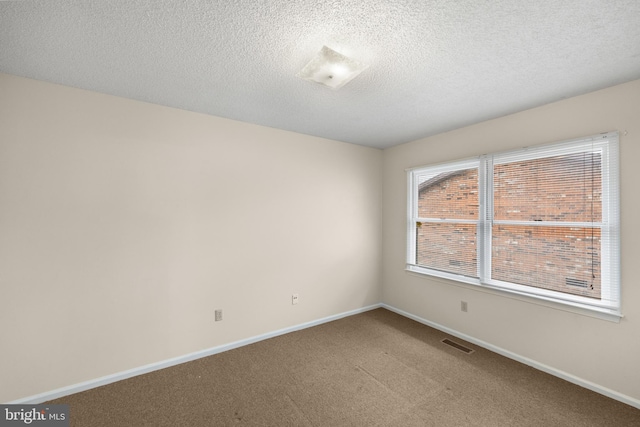 unfurnished room with a textured ceiling and dark carpet