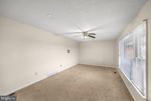 carpeted spare room featuring a textured ceiling and ceiling fan