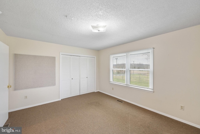 unfurnished bedroom featuring a closet, a textured ceiling, and dark colored carpet