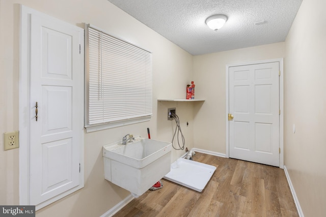 laundry area featuring washer hookup, light hardwood / wood-style floors, and a textured ceiling