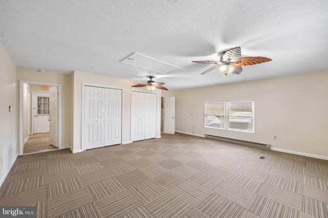 unfurnished bedroom featuring a textured ceiling, multiple closets, ceiling fan, and a baseboard heating unit